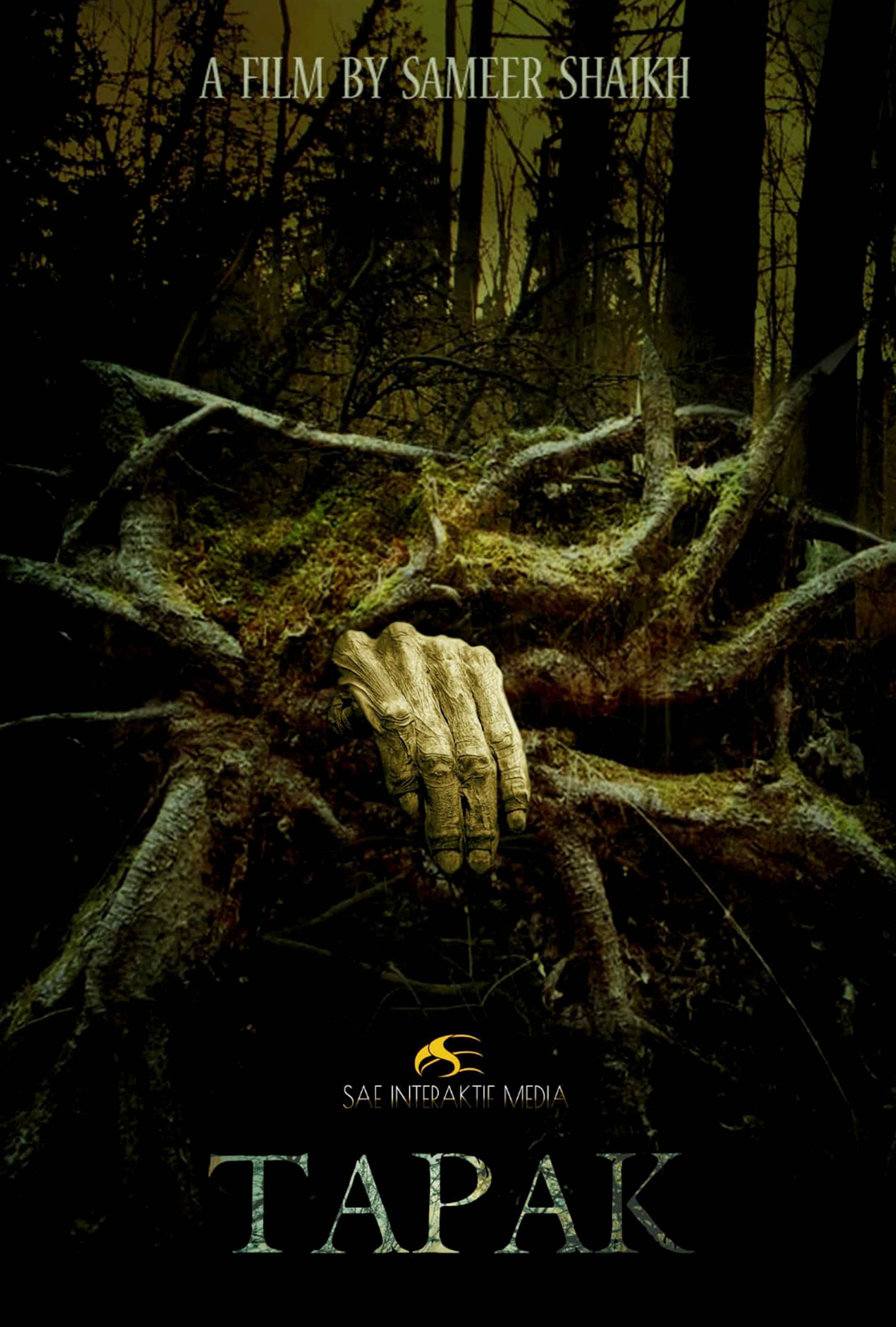 Dark forest scene with twisted tree roots and a human hand emerging from the ground. The scene has an eerie, mysterious atmosphere. Text at the top reads 'A Film by Sameer Shaikh,' and at the bottom is the title 'TAPAK' with a logo and 'SAE Interaktif Media'.